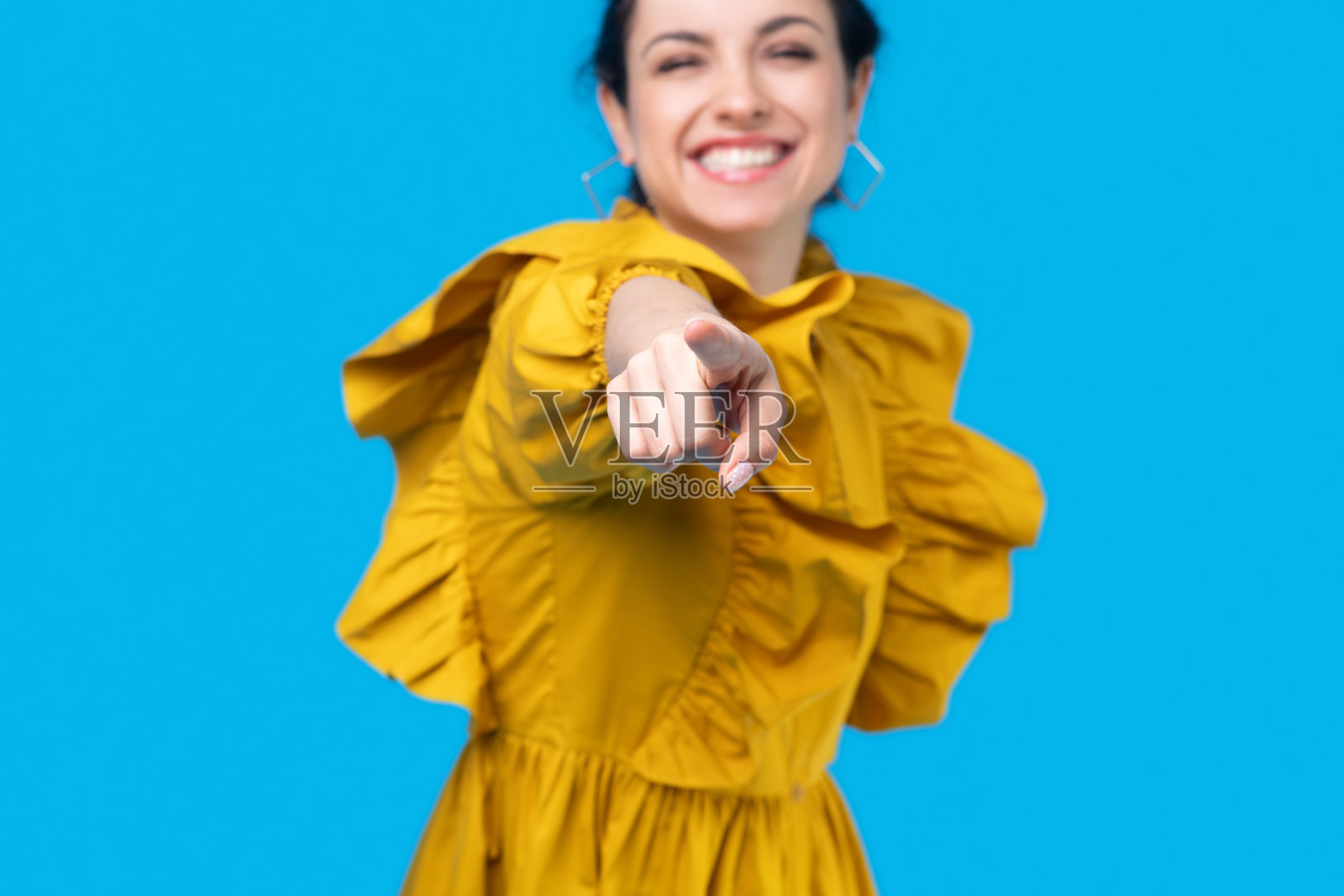 穿着芥末色连衣裙的年轻女子伸展着她的胳膊，大笑着照片摄影图片