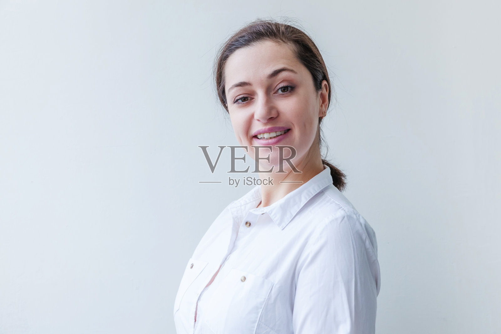 快乐的女孩微笑著，在白色背景下，年轻快乐的积极的棕发女子面部表情照片摄影图片