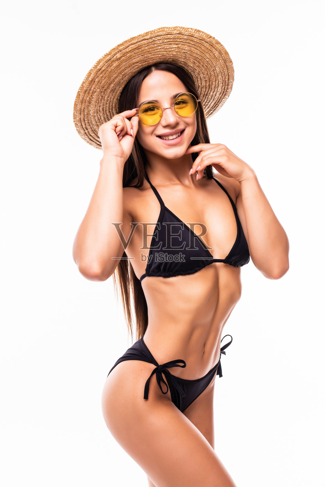 年轻漂亮的女子戴着草帽，墨镜穿着黑色的比基尼孤立在白色的背景照片摄影图片