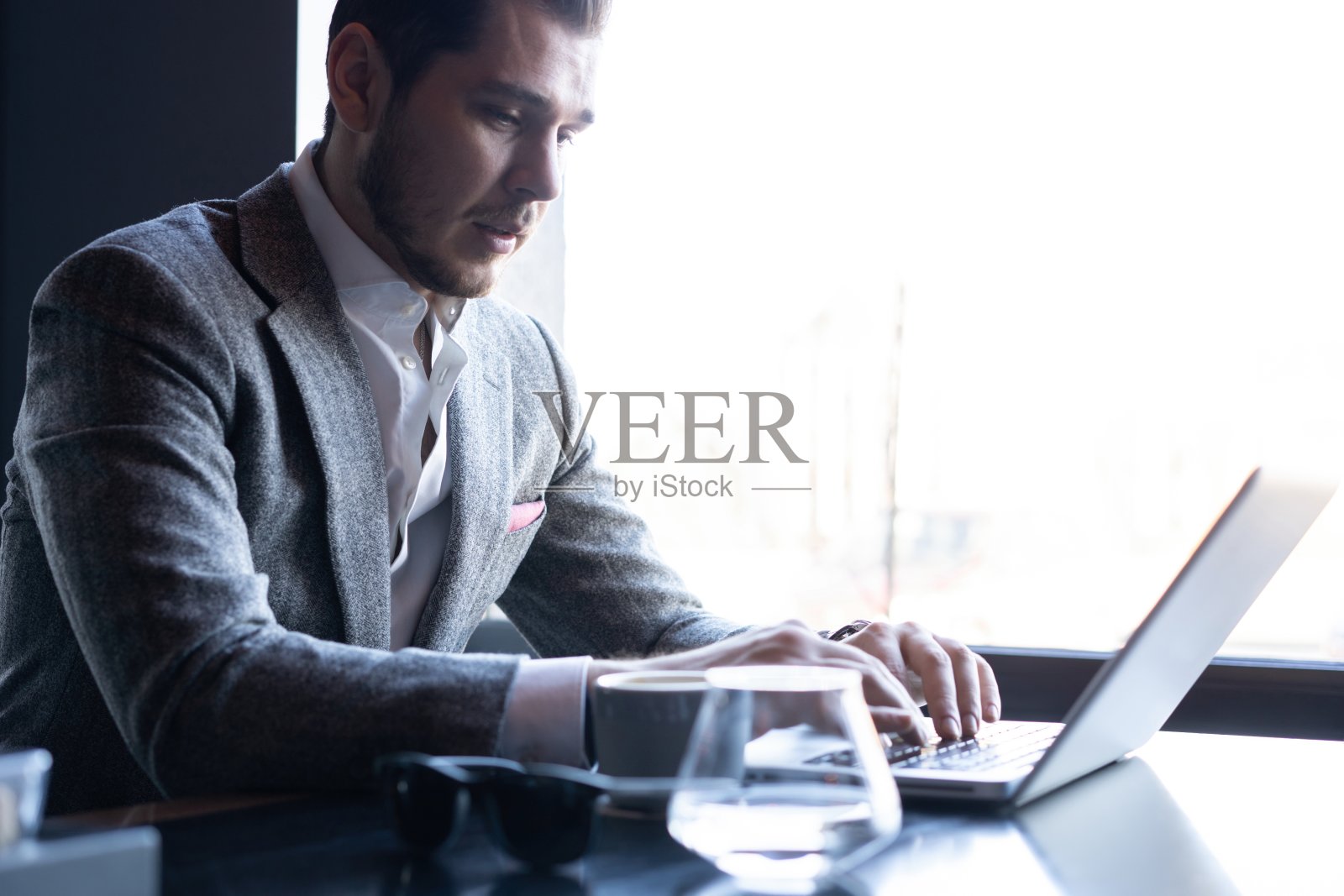 全神贯注：身穿西装的年轻男人在咖啡馆使用电脑照片摄影图片