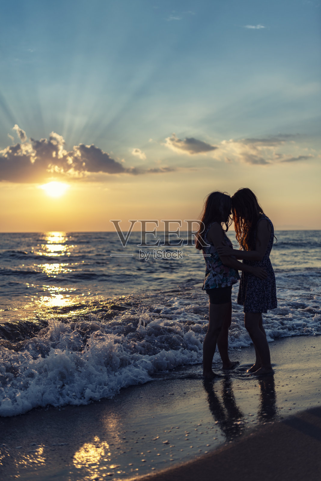 两位女士在意大利海滩日落时照片摄影图片