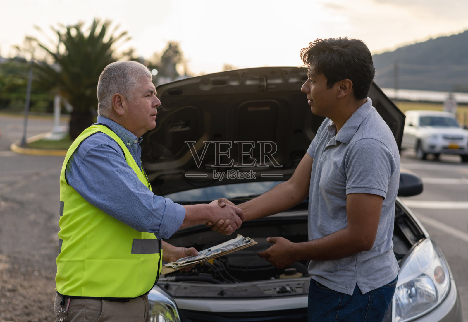 男顾客与刚提供路边援助的成熟机械师握手照片摄影图片