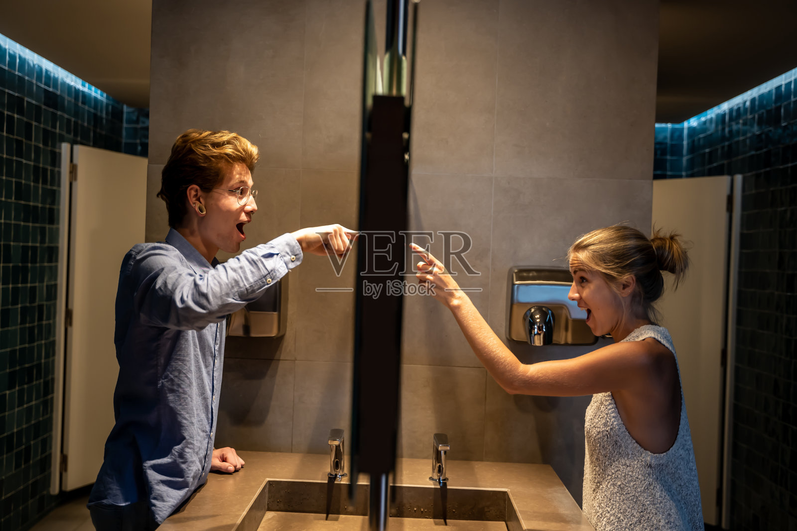 在浴室镜子两侧指着镜子的男人和女人照片摄影图片