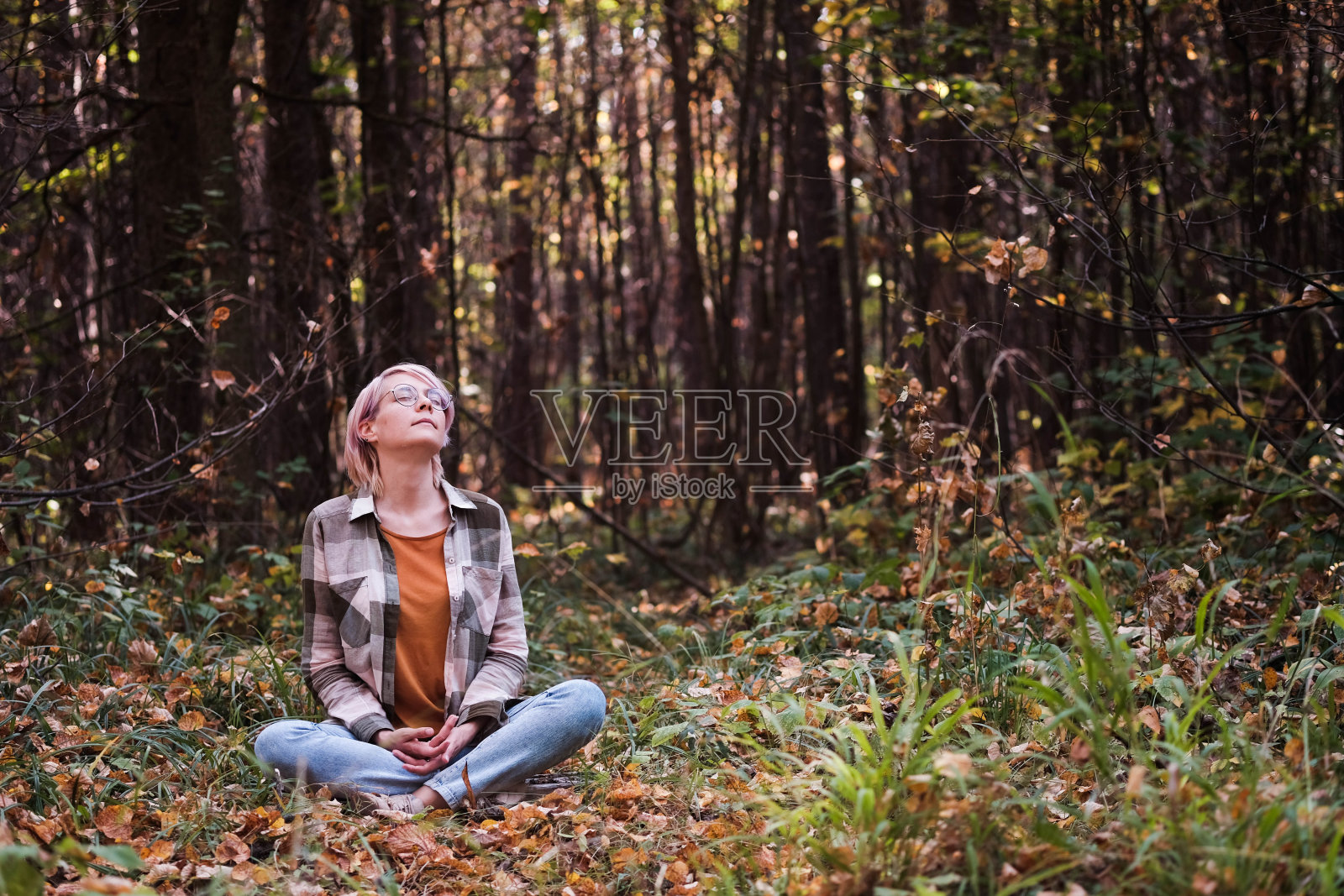 在森林中冥想的金发年轻女人，享受大自然。生态系统中自然与人之间连接的概念照片摄影图片
