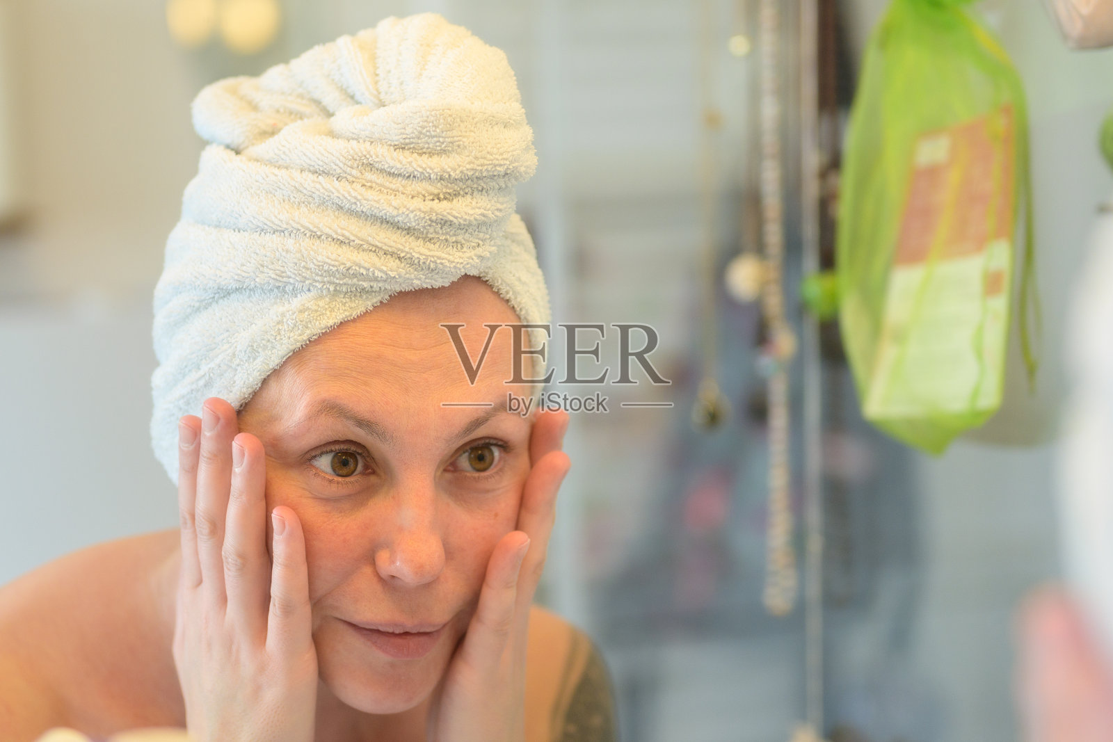 中年妇女在镜子里检查自己的脸照片摄影图片