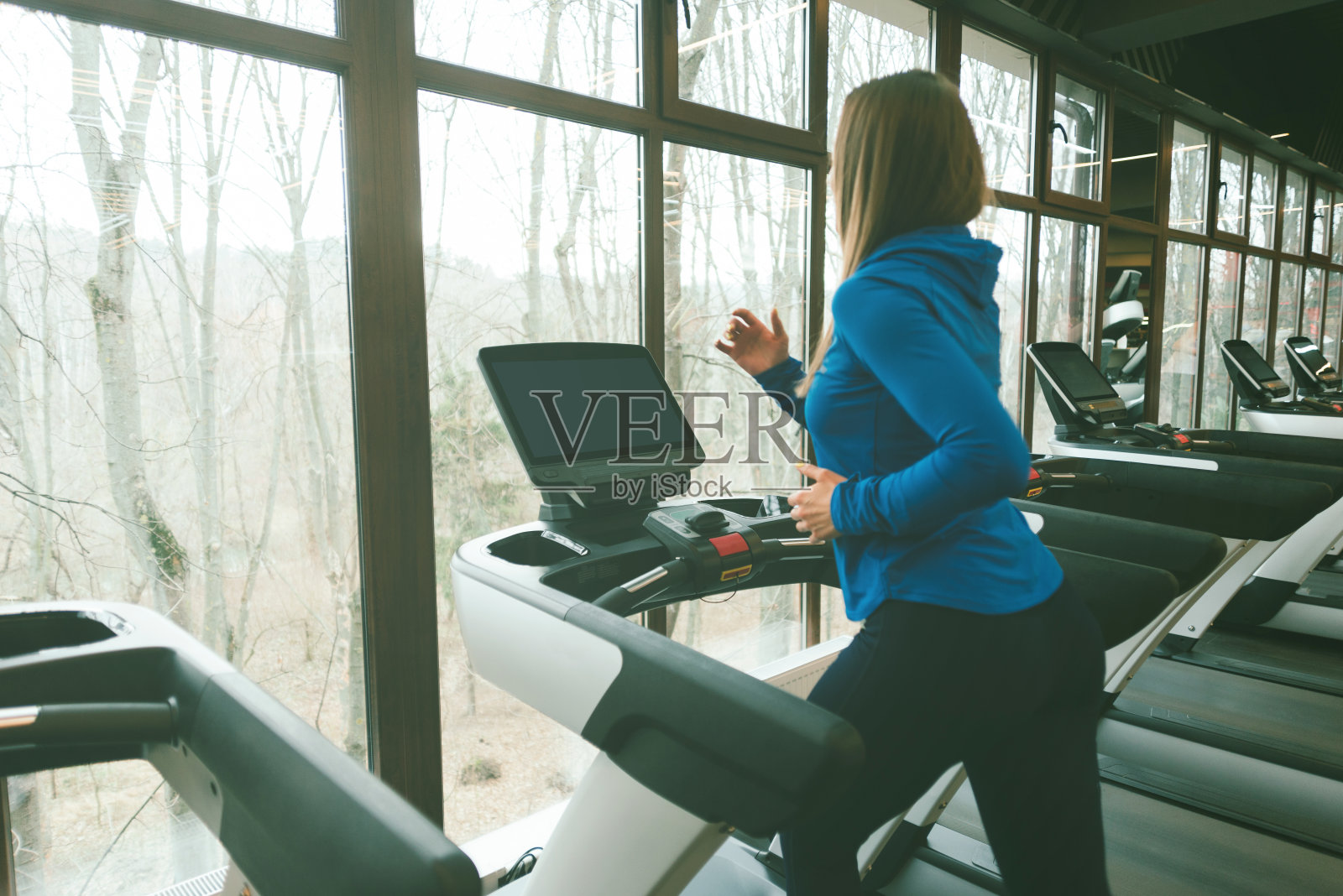 年轻的运动女性在健身房跑步机上跑步，早上运动时间照片摄影图片
