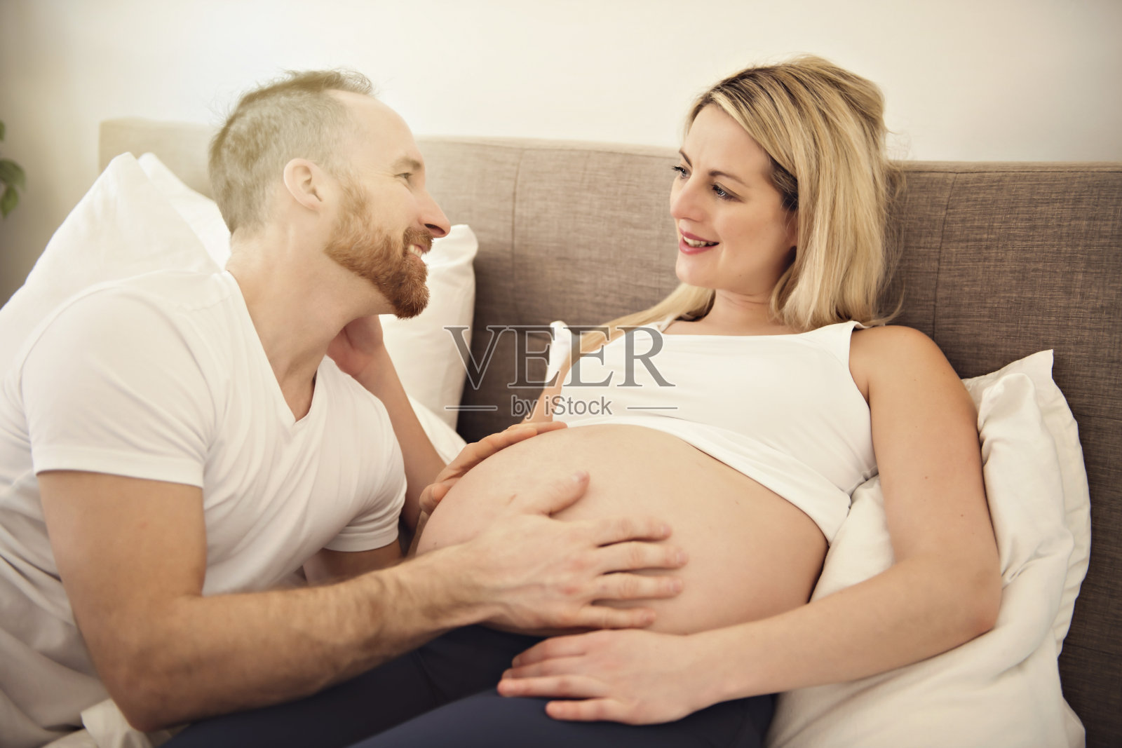美丽的孕妇和她英俊的丈夫在床上共度时光照片摄影图片