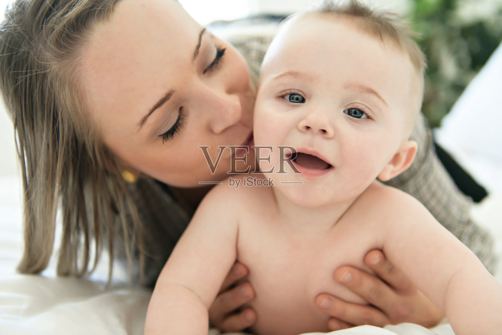 年轻母亲在床上抱着她的婴儿照片摄影图片