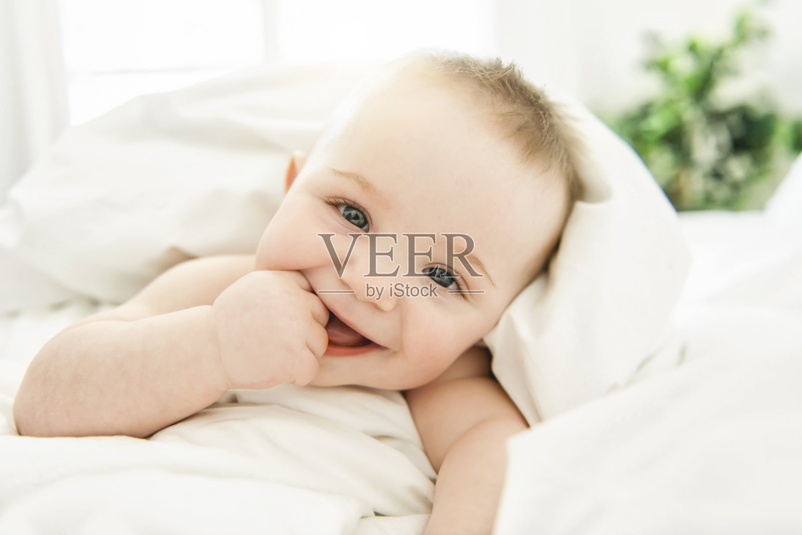 可爱的小男孩躺在白色的床上照片摄影图片