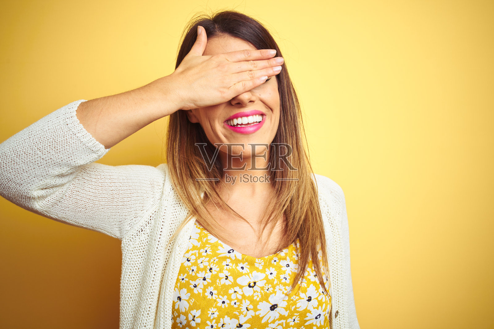 年轻美丽的女人穿着夹克站在黄色孤立的背景微笑和大笑，手捂着脸遮住眼睛惊讶。盲目的概念。照片摄影图片