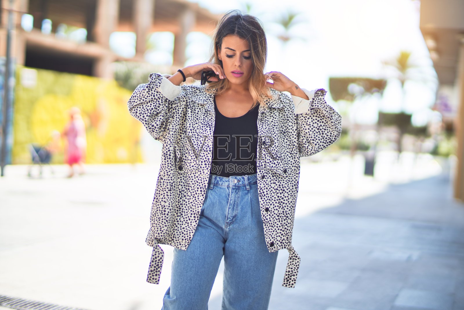 年轻漂亮的女人微笑着，快乐而自信。在镇上的街道上站立和行走照片摄影图片