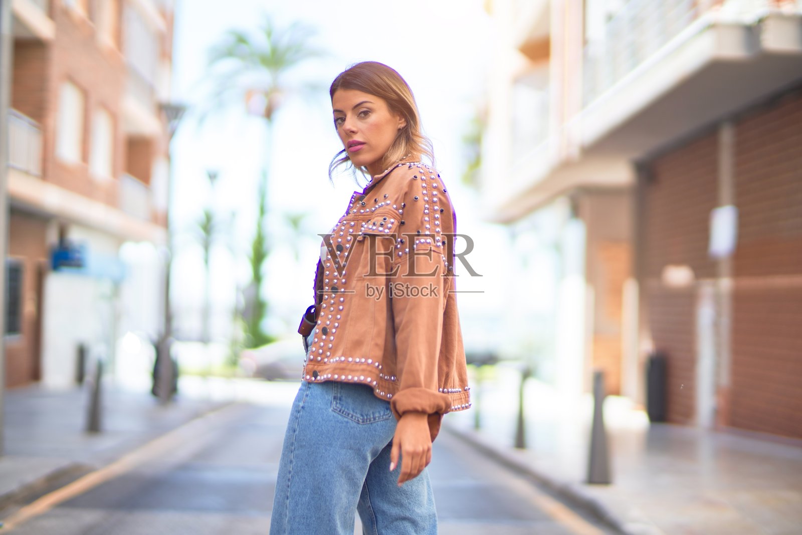 年轻漂亮的女人微笑着，快乐而自信。在镇上的街道上站立和行走照片摄影图片