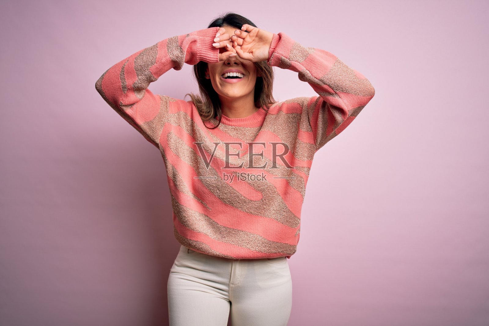 年轻漂亮的女人穿着时尚的都市服装，模特穿着休闲街头风格站在粉红色的背景照片摄影图片