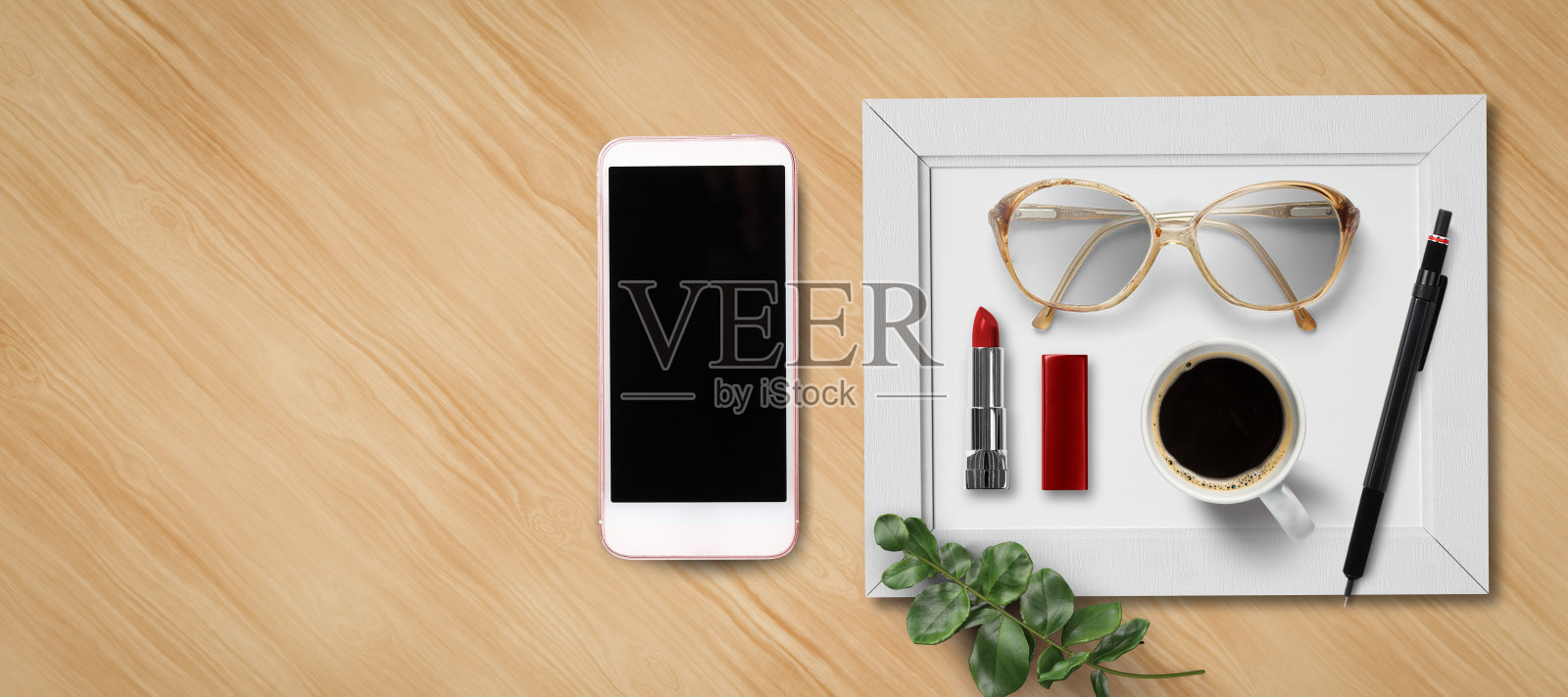 女性平躺着，拿着智能手机、口红、眼镜、咖啡和一支笔照片摄影图片