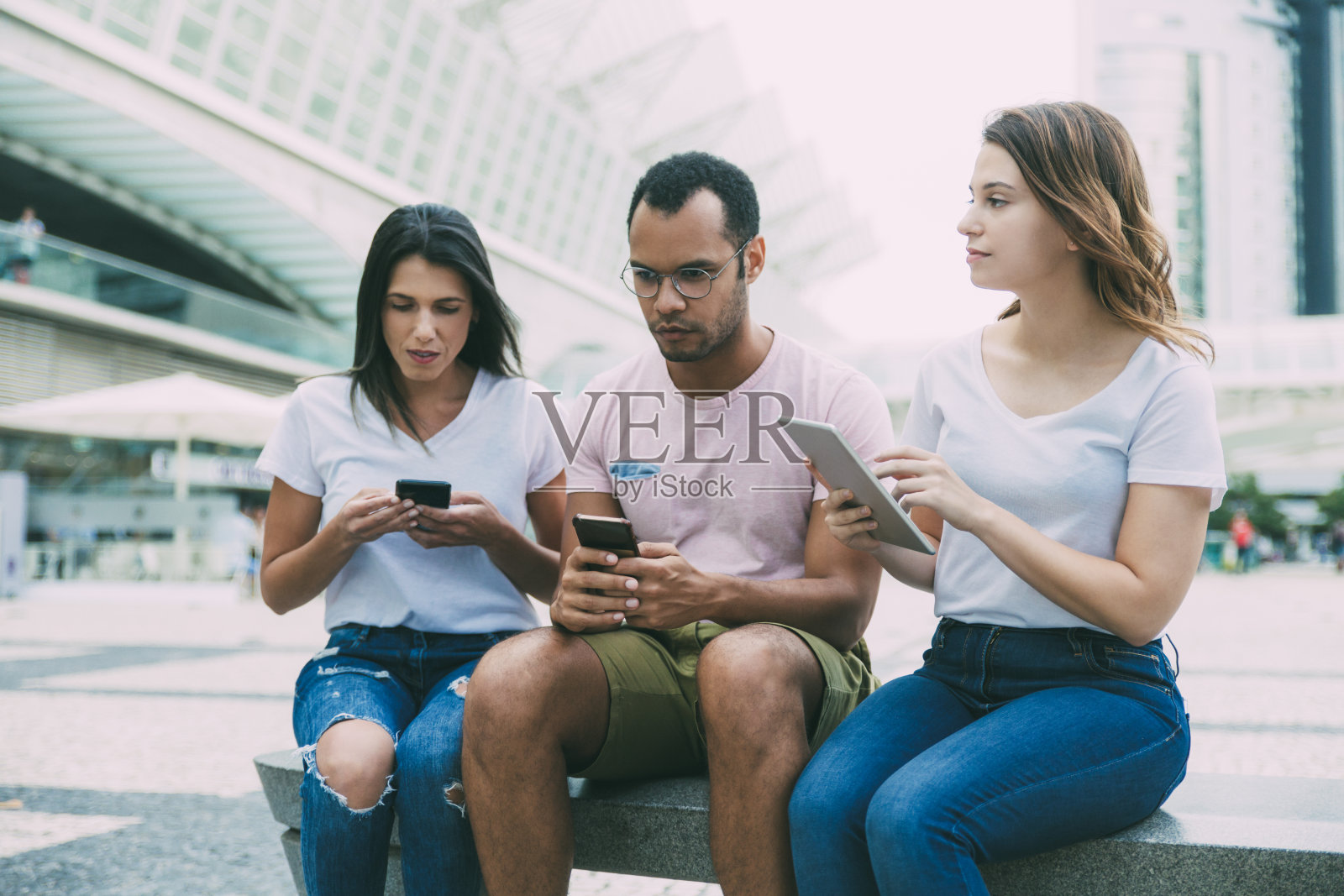 坐在街上使用数码设备的年轻人照片摄影图片