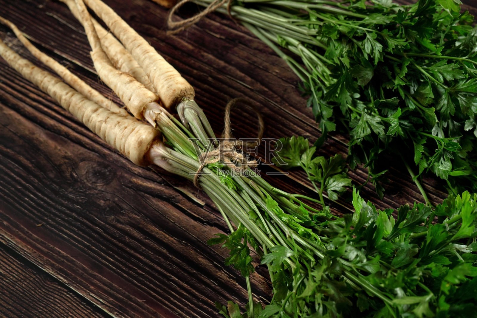 一束带绿叶的防风草根，铺在旧木板上照片摄影图片