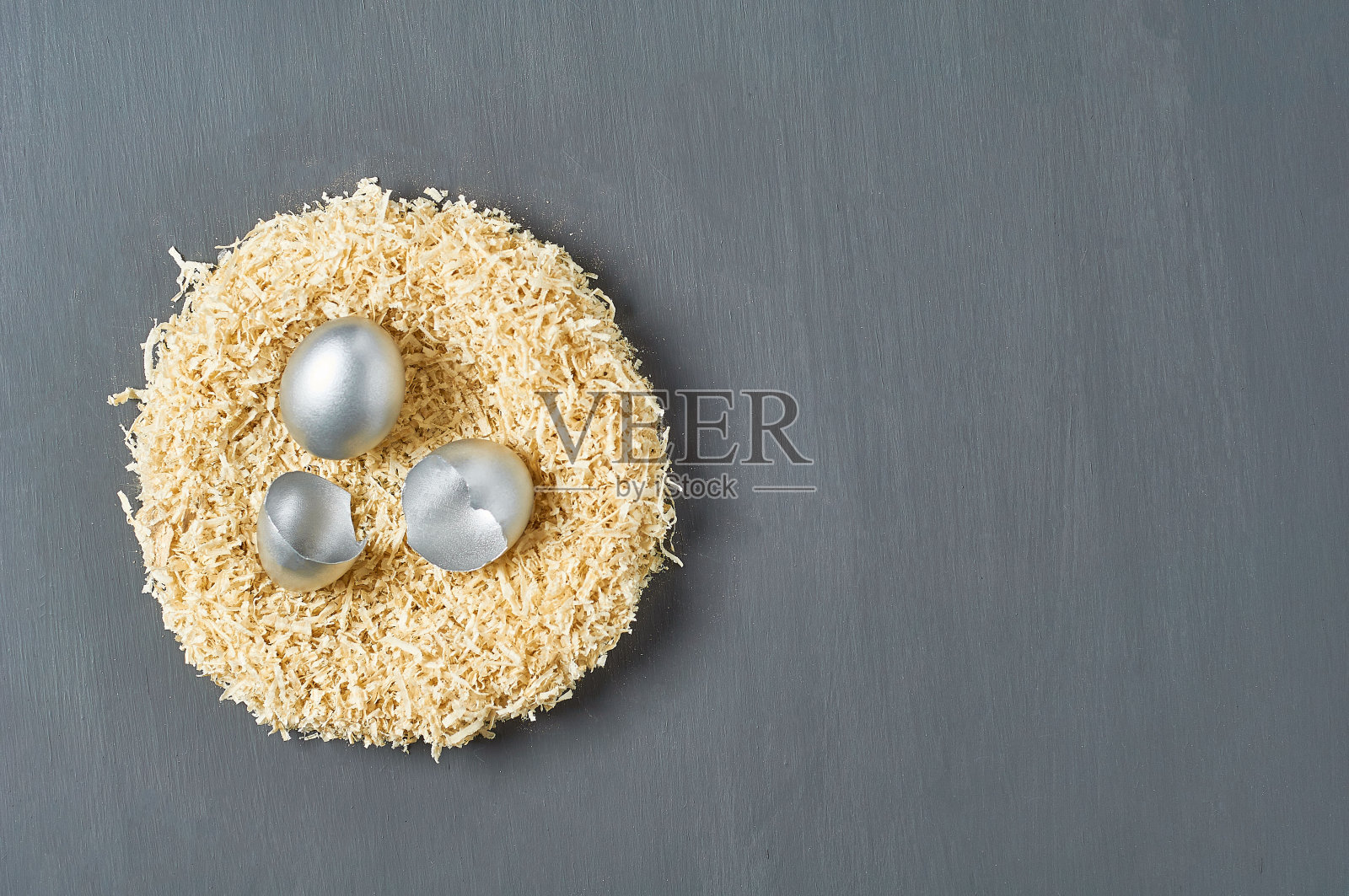 在黑色的混凝土背景下，画上银色的鸡蛋和贝壳躺在巢里。复活节的概念。成功商业和投资的象征。副本的空间。俯视图照片摄影图片