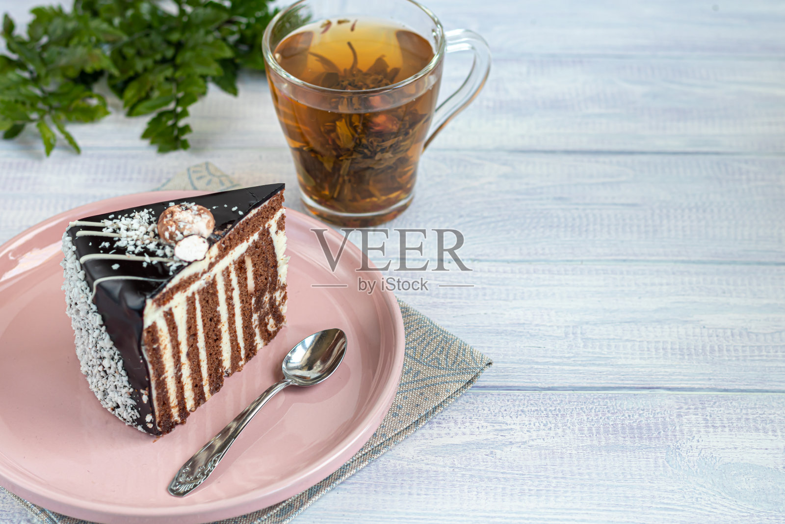 一块有巧克力糖衣的斑马蛋糕。在一个灯光背景上。背景是一个放着花茶的杯子。照片摄影图片