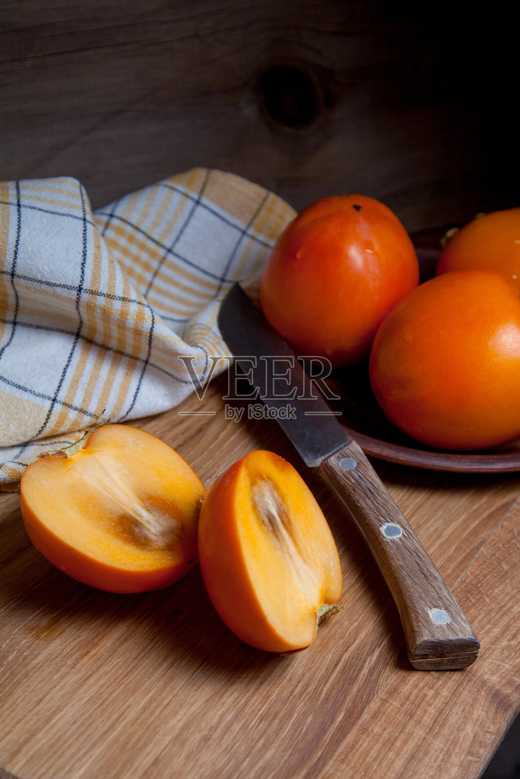 整个成熟的柿子和切片的水果放在木质背景上。照片摄影图片