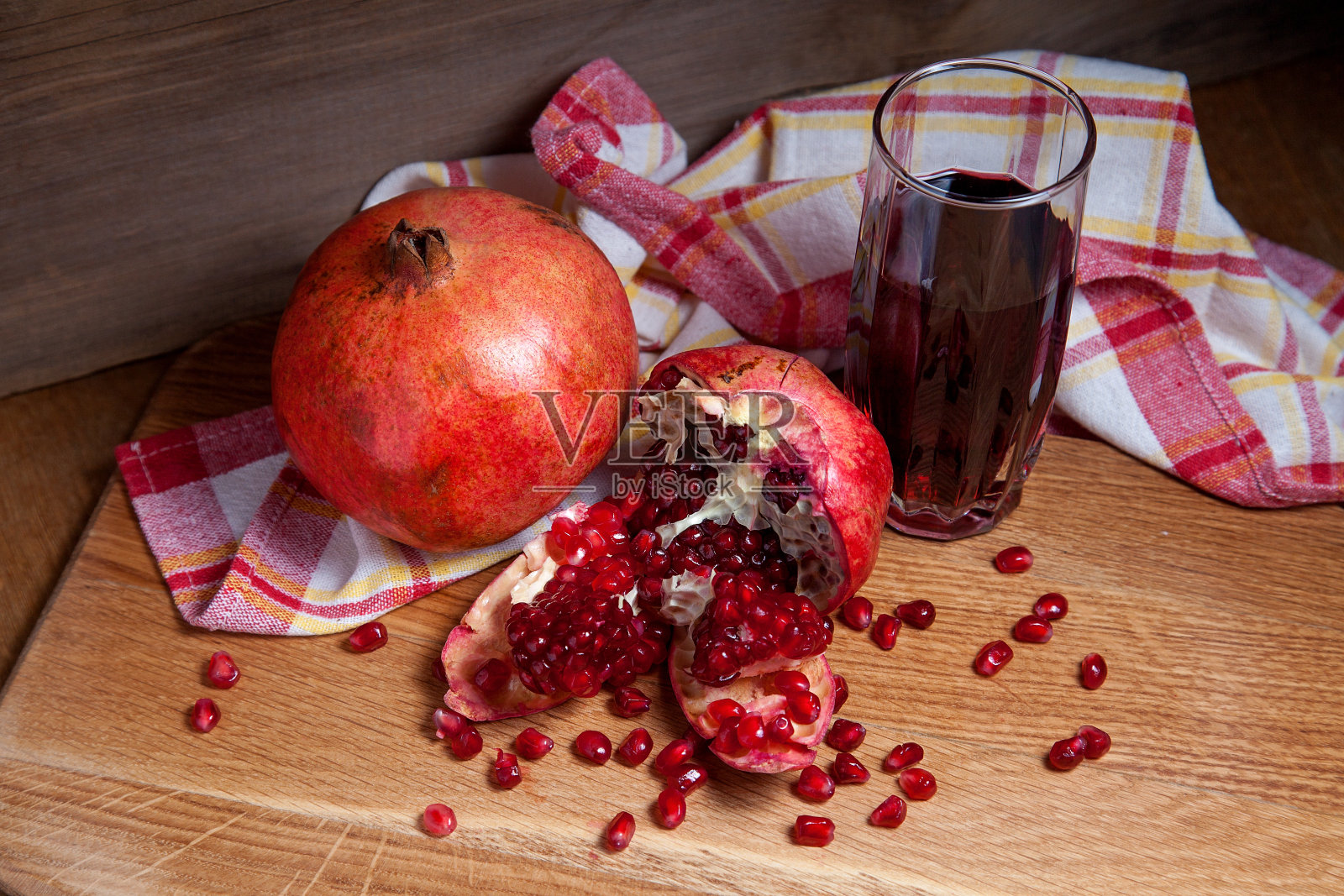 新鲜的红石榴和一杯新鲜的鲁迪果汁在一个木制的背景。照片摄影图片
