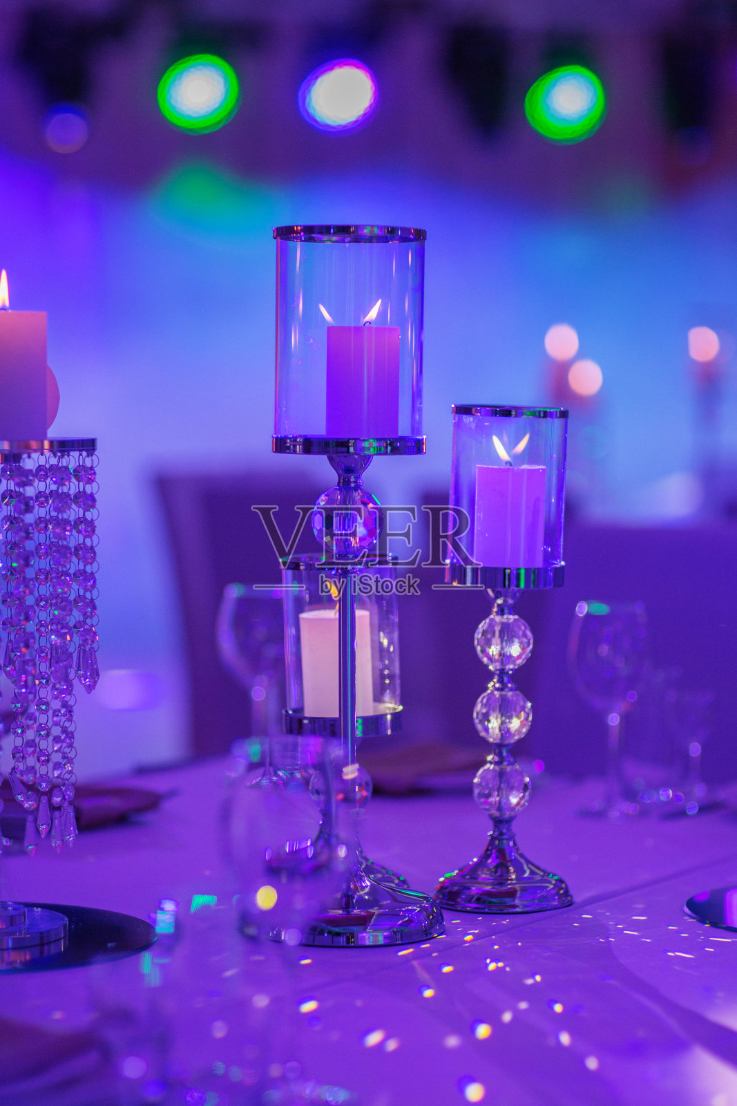 桌子上有一个水晶做的烛台，上面插着白色的蜡烛。用蓝光装饰节日或庆典用蓝光装饰有选择性的重点。结婚的那一天。照片摄影图片