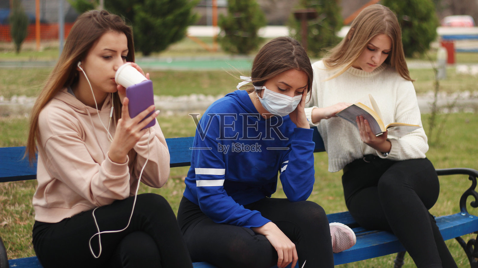 三个十几岁的女孩，一个戴着面具照片摄影图片