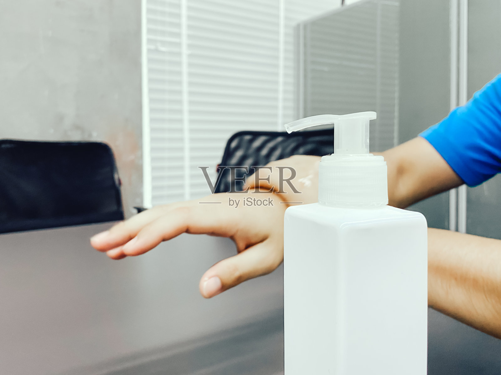 在办公室使用酒精凝胶洗手，以保护COVID-19病毒。照片摄影图片