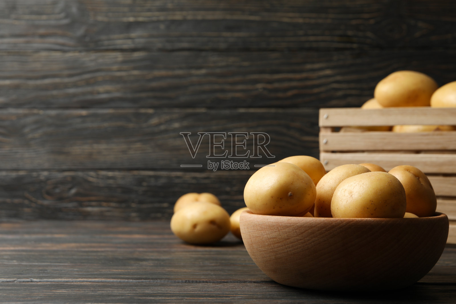 碗和篮子与年轻的土豆在木背景，文字空间照片摄影图片