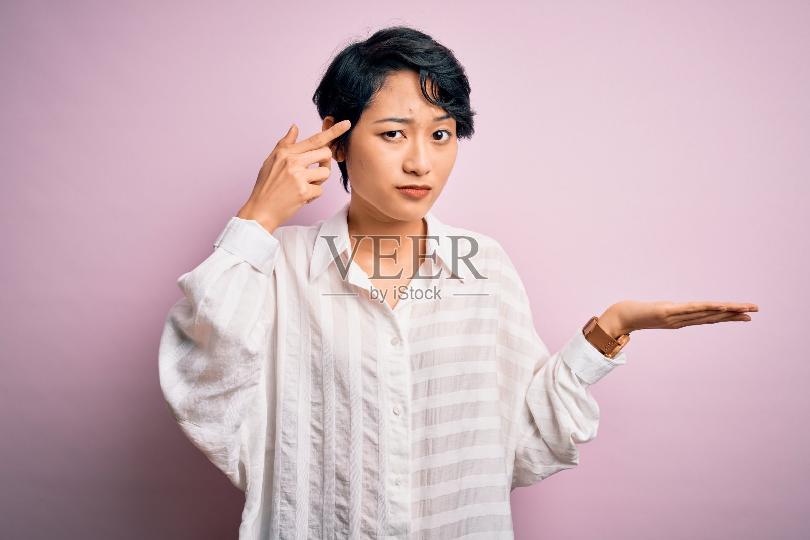 年轻美丽的亚洲女孩穿着休闲衬衫站在孤立的粉红色背景困惑和恼火的手掌显示拷贝空间和指向额头。想想。照片摄影图片