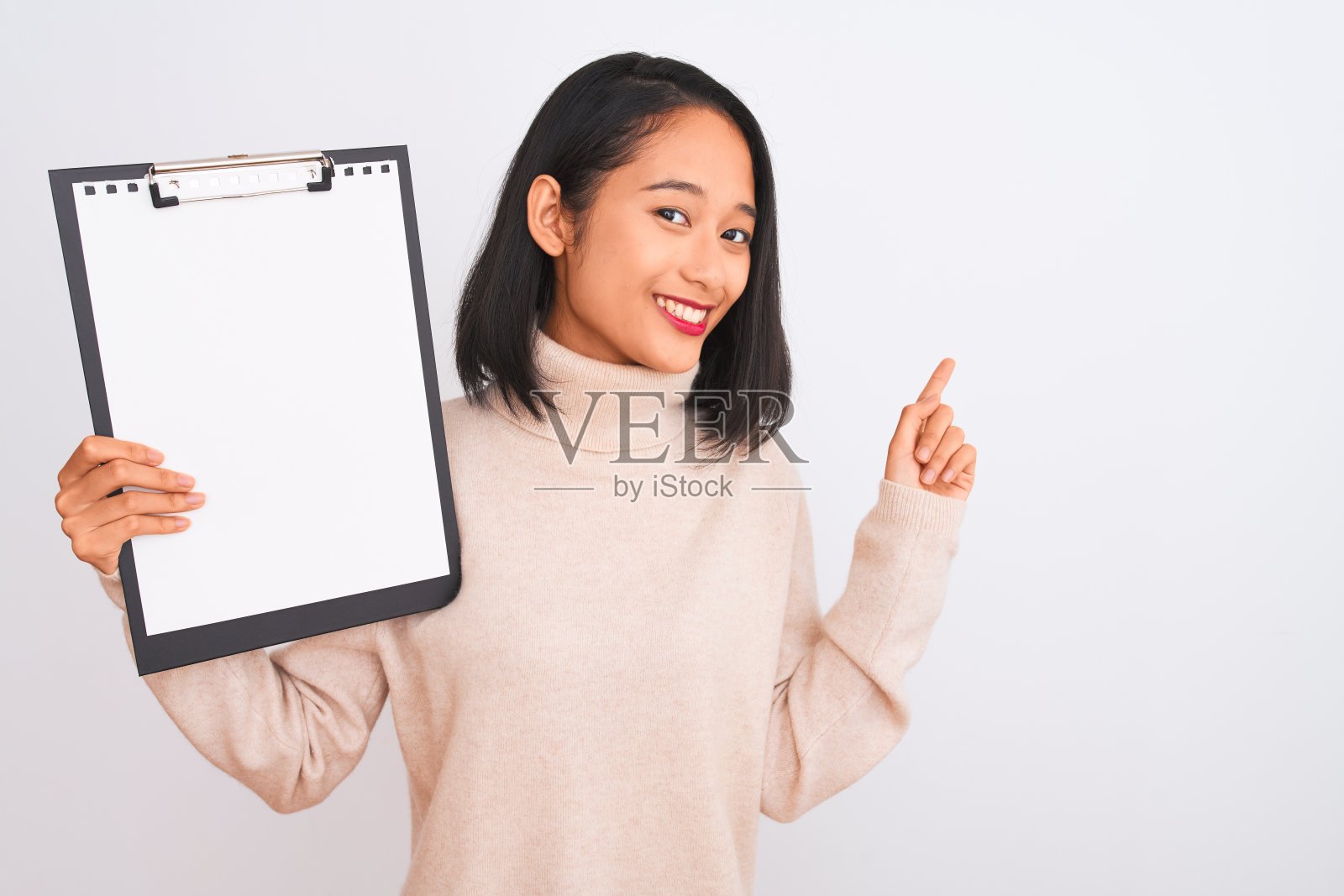 年轻的中国女检查员拿着剪贴板站在孤立的白色背景非常高兴地用手和手指指着一边照片摄影图片