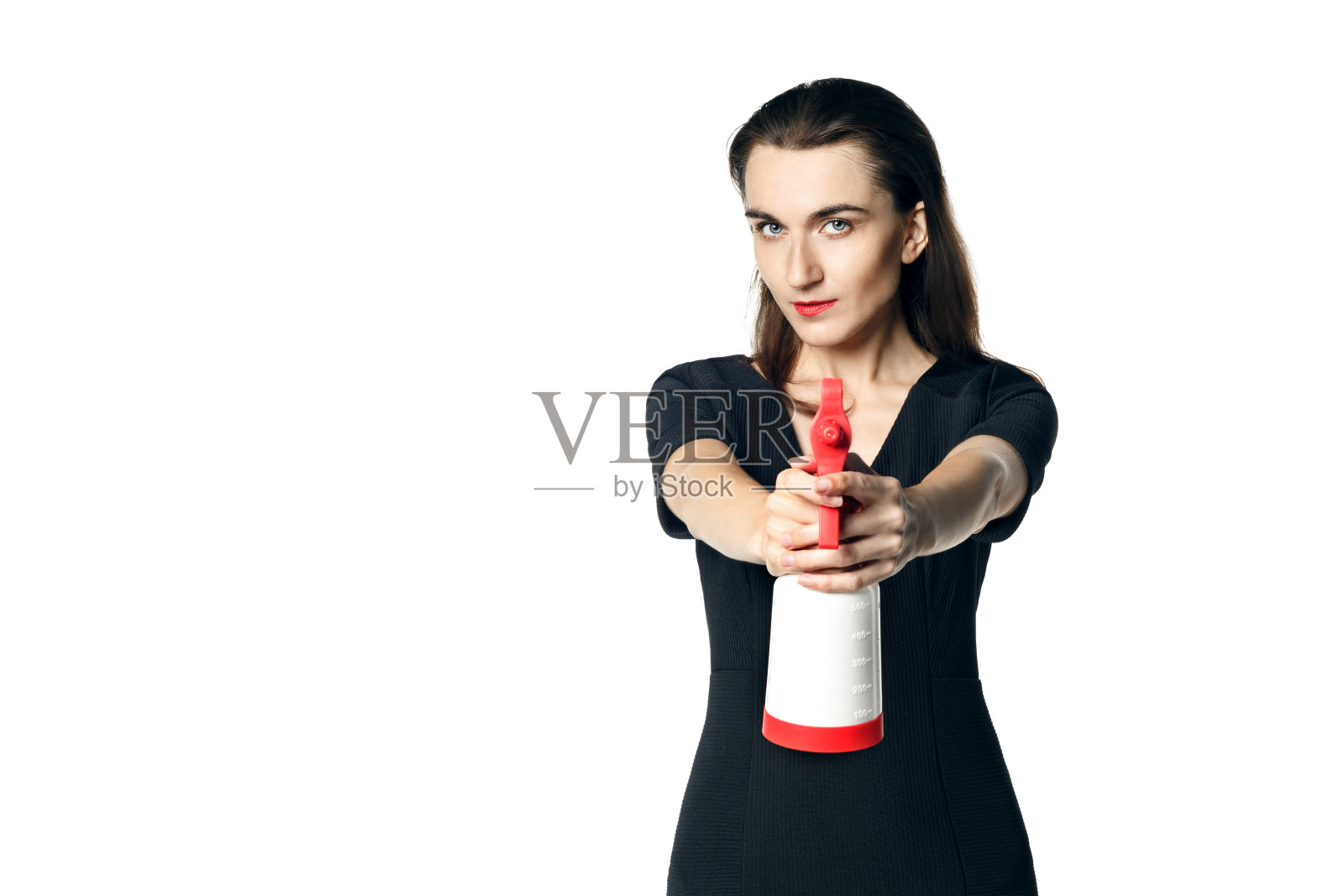 穿着黑色连衣裙，拿着玻璃清洁剂，假装是特工的迷人女人。在白色背景下隔离照片摄影图片