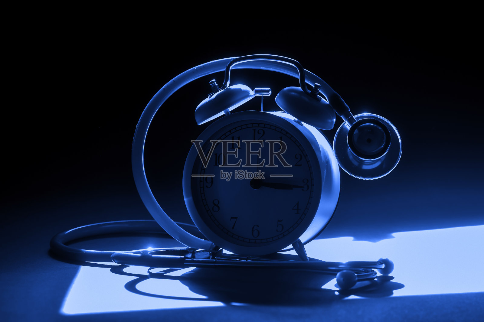 医用红色听诊器和闹钟。冠状病毒隔离。病毒大流行防护概念。蓝色的过滤器照片摄影图片