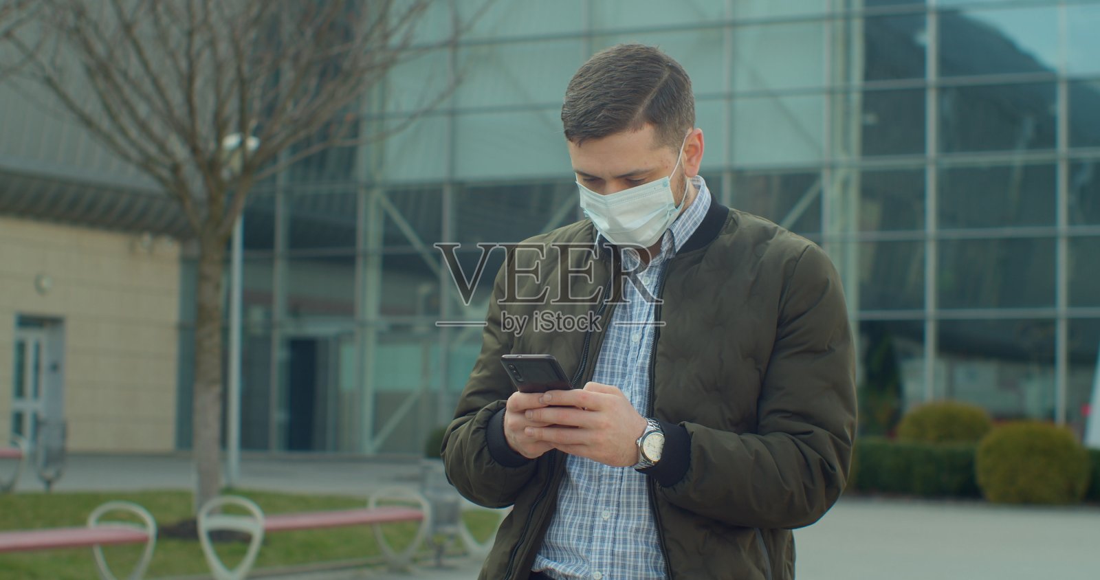 佩戴防护口罩的青年男子使用电话COVID-19冠状病毒感染机场附近的大流行性疾病病毒男性游客流行病空气卫生。照片摄影图片