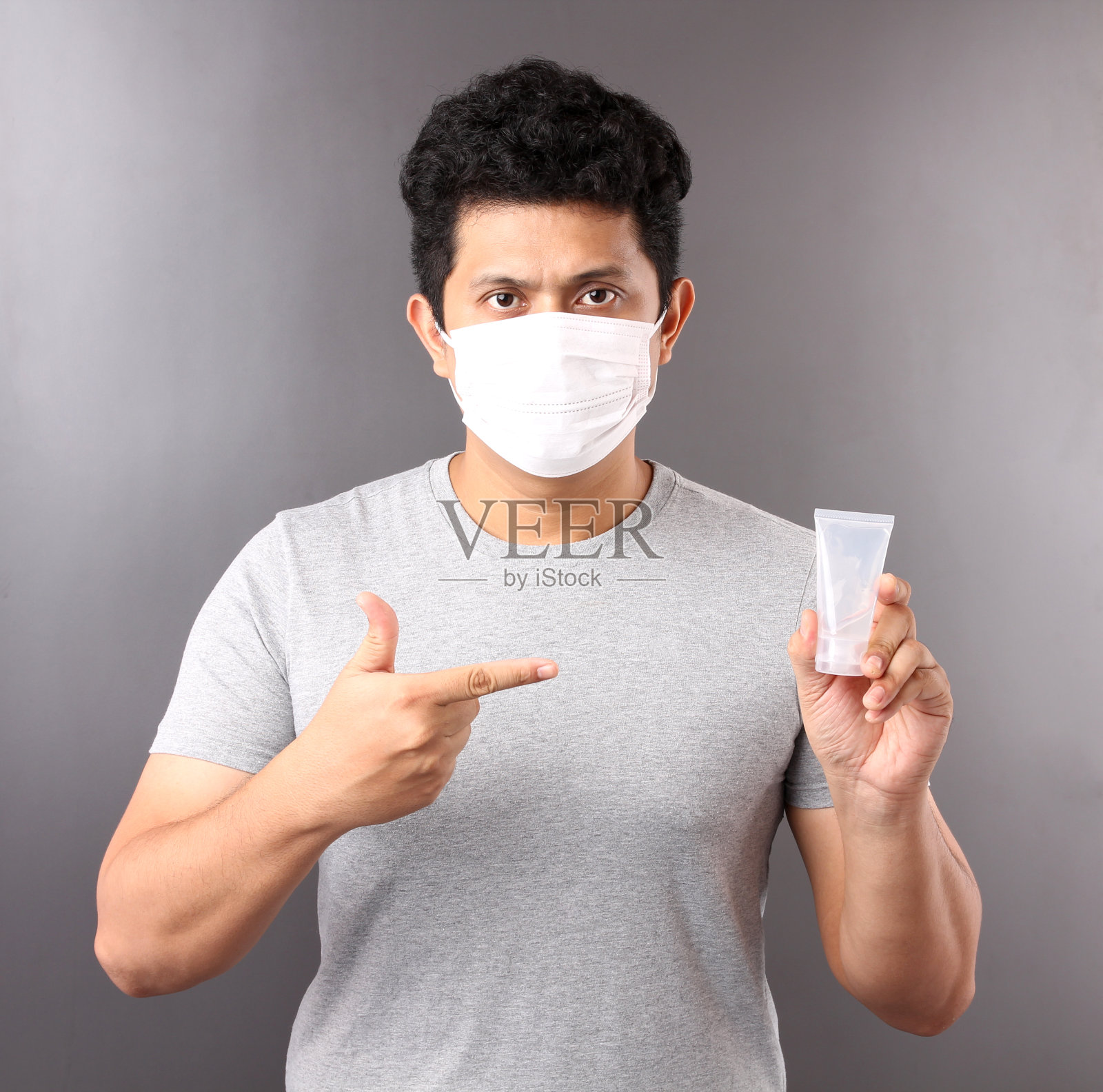 使用酒精凝胶并戴医用口罩的帅气亚洲男人，建议预防病毒和各种疾病，在灰色背景演播室隔离照片摄影图片