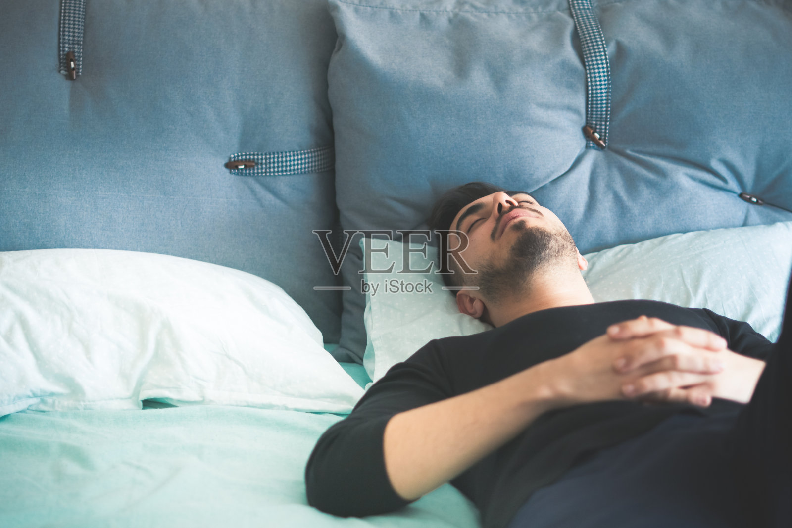 一个年轻人躺在家里的床上。照片摄影图片