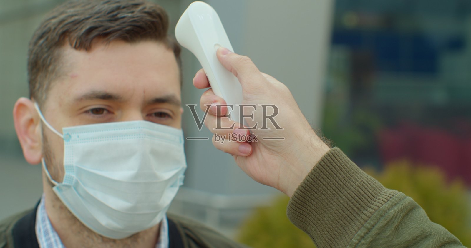 新冠疫情体温测量：正在测量一名男子的体温，以控制疾病。照片摄影图片