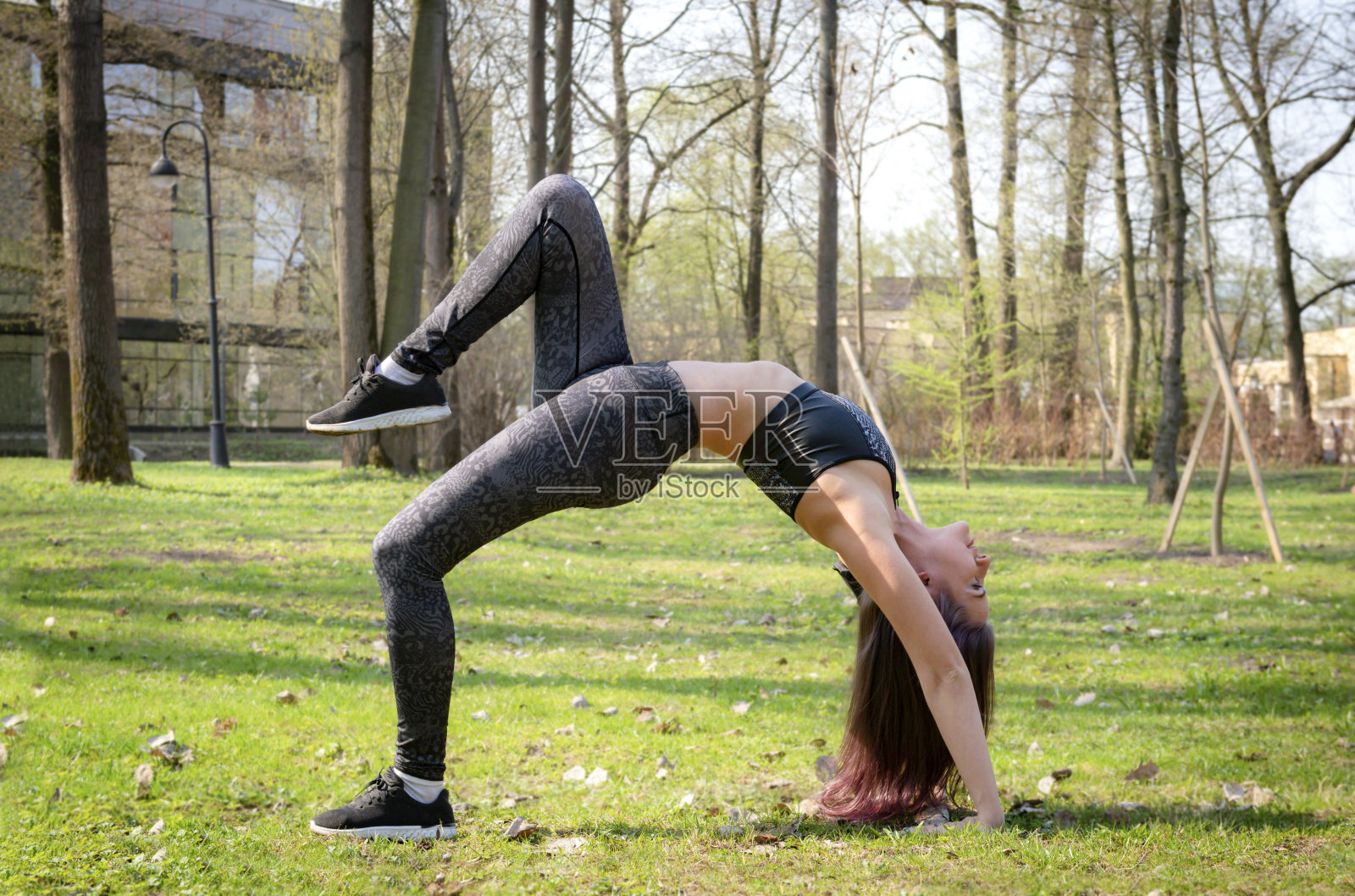 年轻白人女子在公园草地上做桥式瑜伽照片摄影图片
