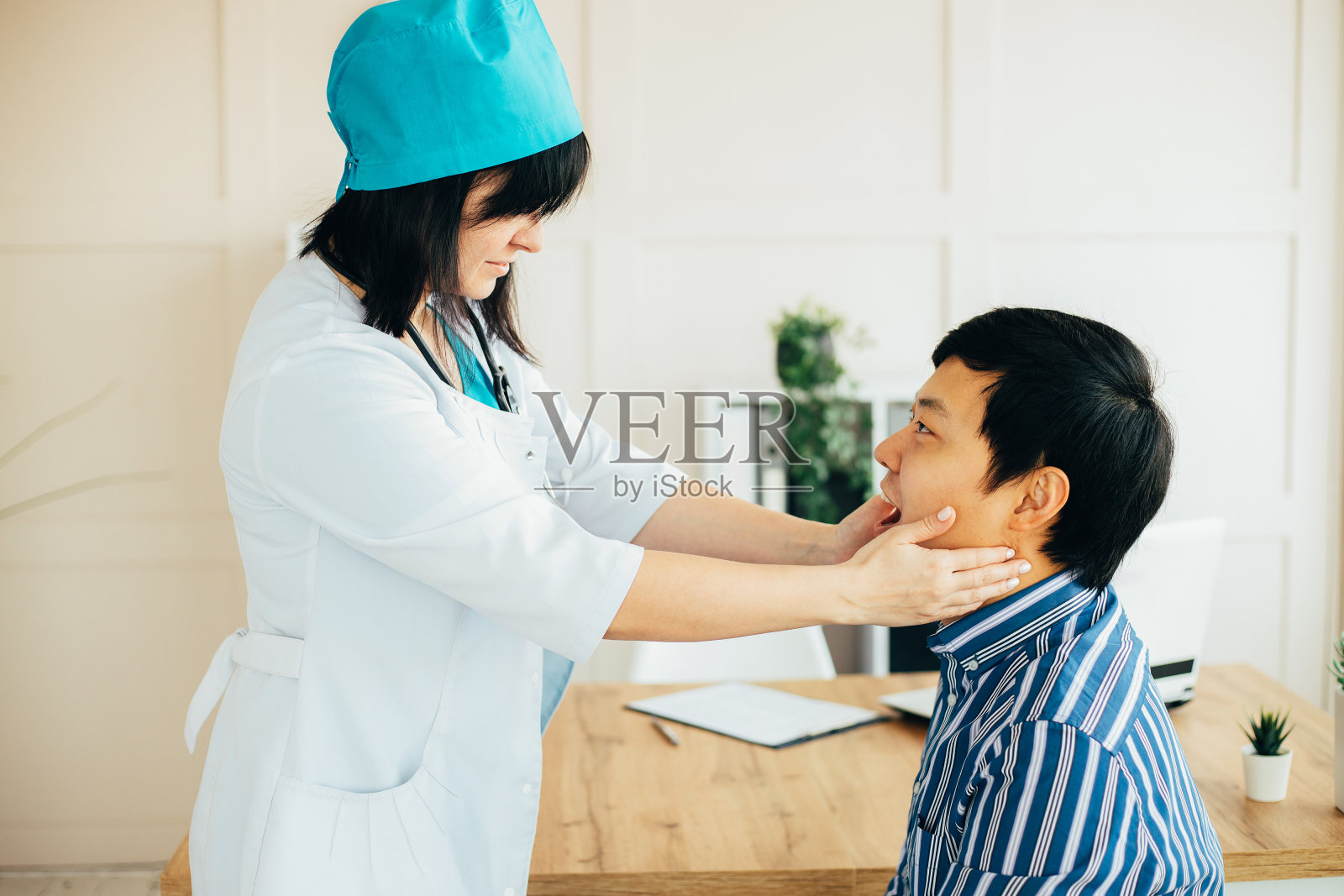 亚裔医生在诊所检查男病人照片摄影图片