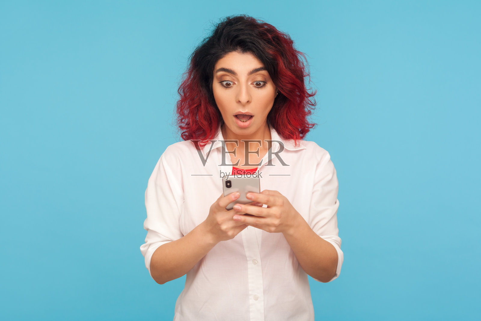 惊讶的时尚红发时髦女人用手机的肖像，对突如其来的消息感到震惊照片摄影图片