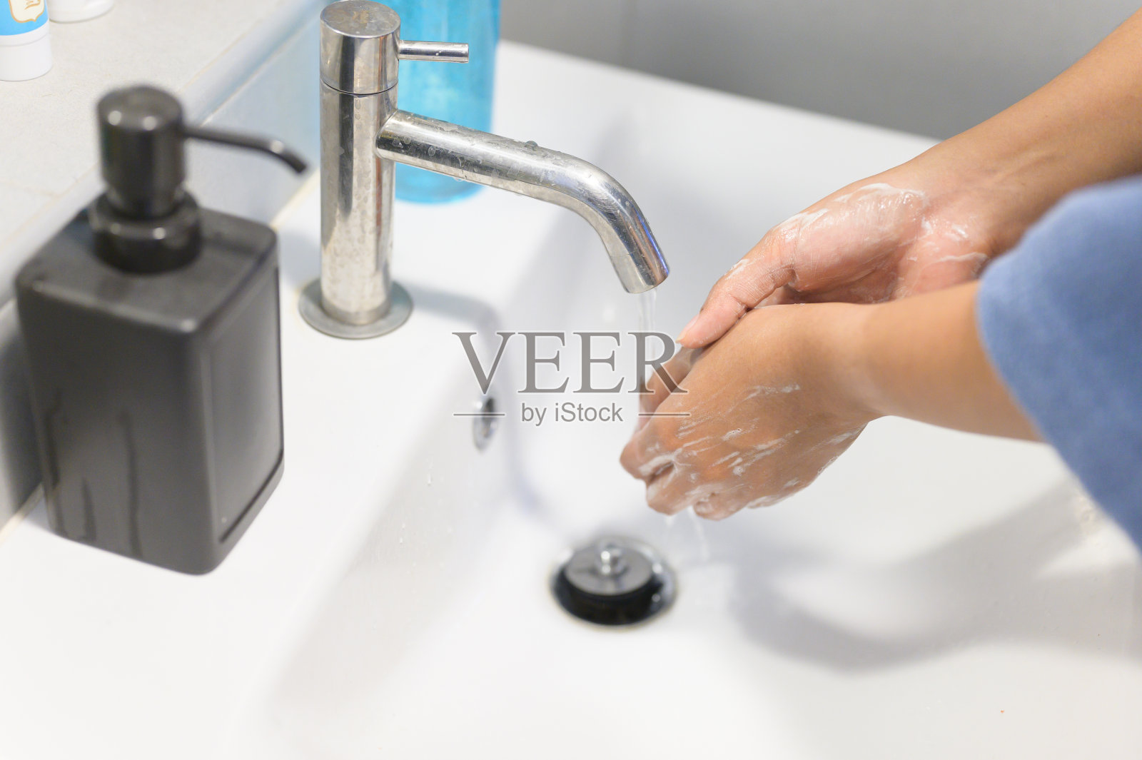 妇女使用酒精洗手液洗手，以防止感染Covid-19病毒和其他病毒。照片摄影图片