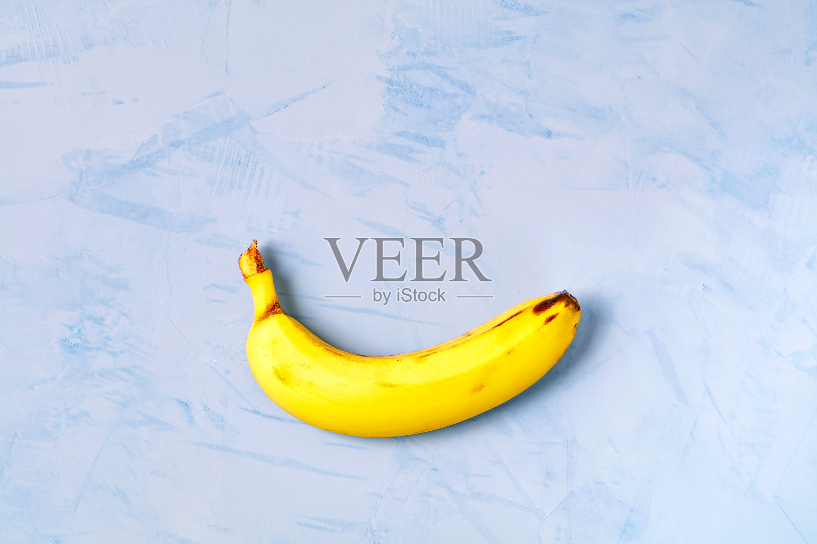 成熟的黄香蕉躺在蓝色的混凝土背景上。照片摄影图片