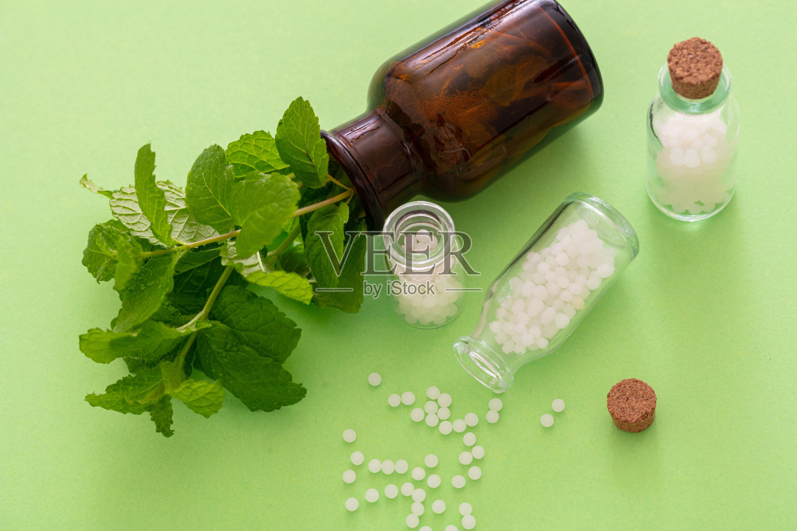 顺势疗法，玻璃瓶子里散落着小球，绿色背景照片摄影图片