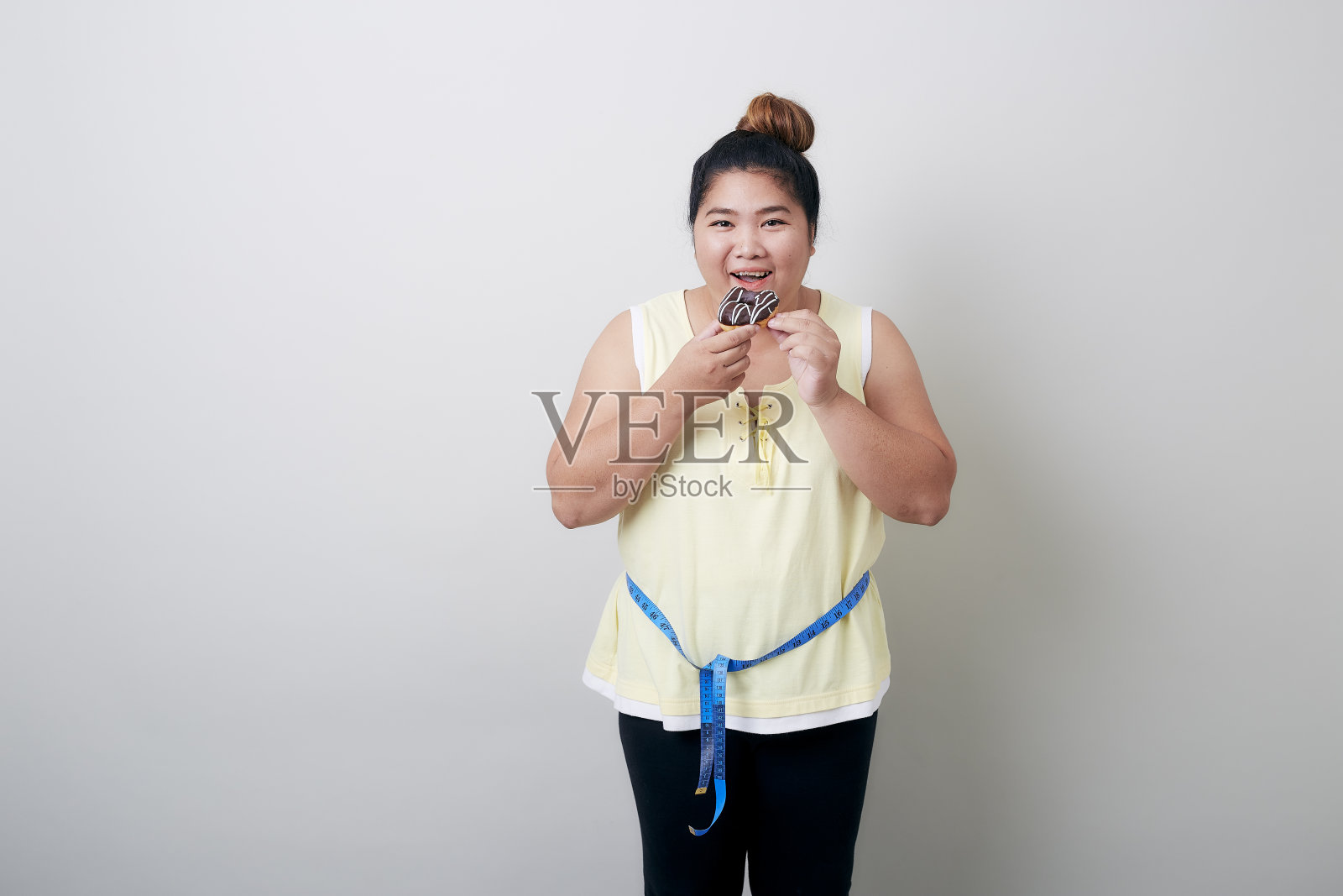 在灰色背景上测量食物的超重女性照片摄影图片