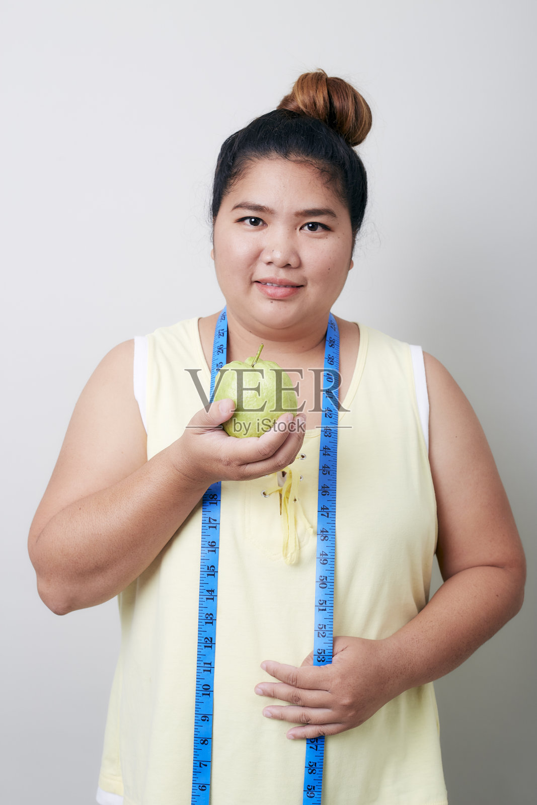 在灰色背景上测量食物的超重女性照片摄影图片