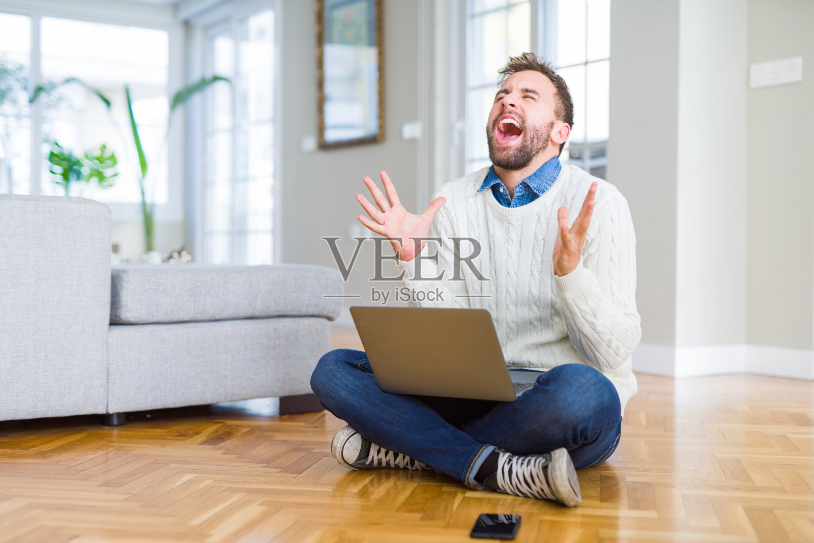 使用笔记本电脑的英俊男人，因成功而疯狂庆祝照片摄影图片