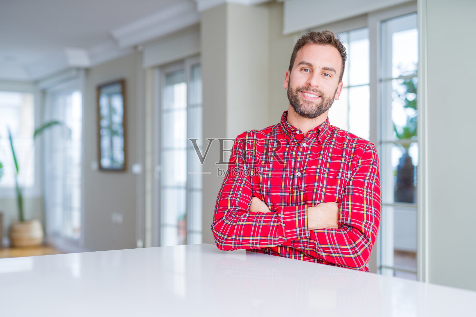 穿着彩色衬衫，面带微笑，双臂交叉，看着镜头的英俊男人。积极的人。照片摄影图片