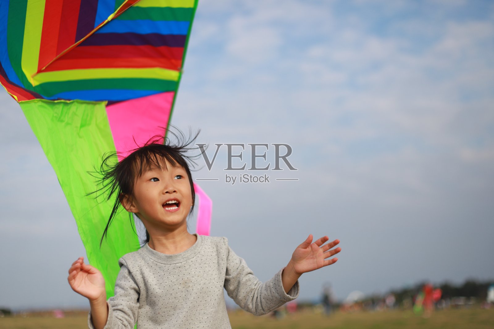 亚洲女孩在草地上玩和放风筝。照片摄影图片