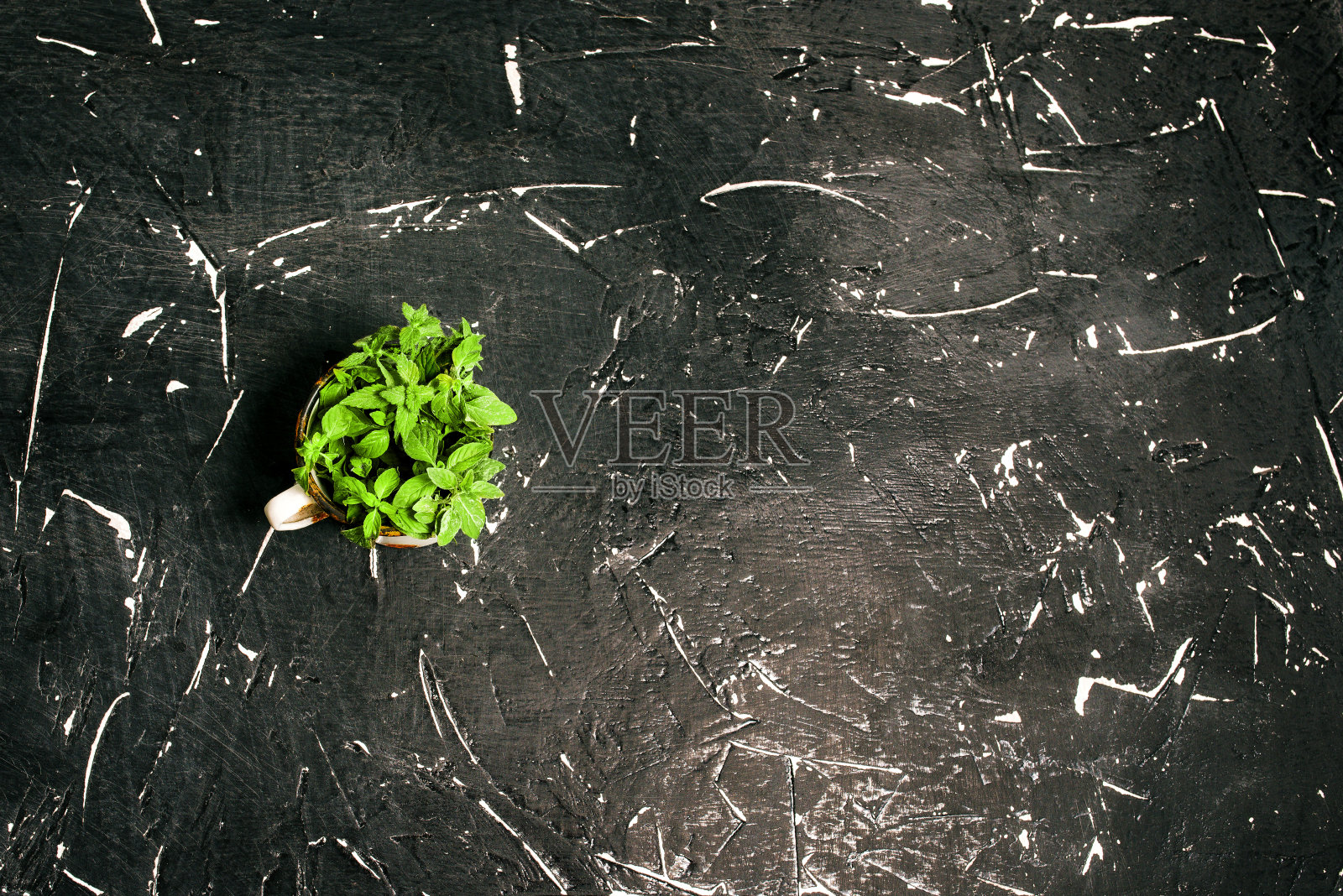 用金属杯清洗的叶子，表面有黑色纹理。俯视图，复制空间。照片摄影图片