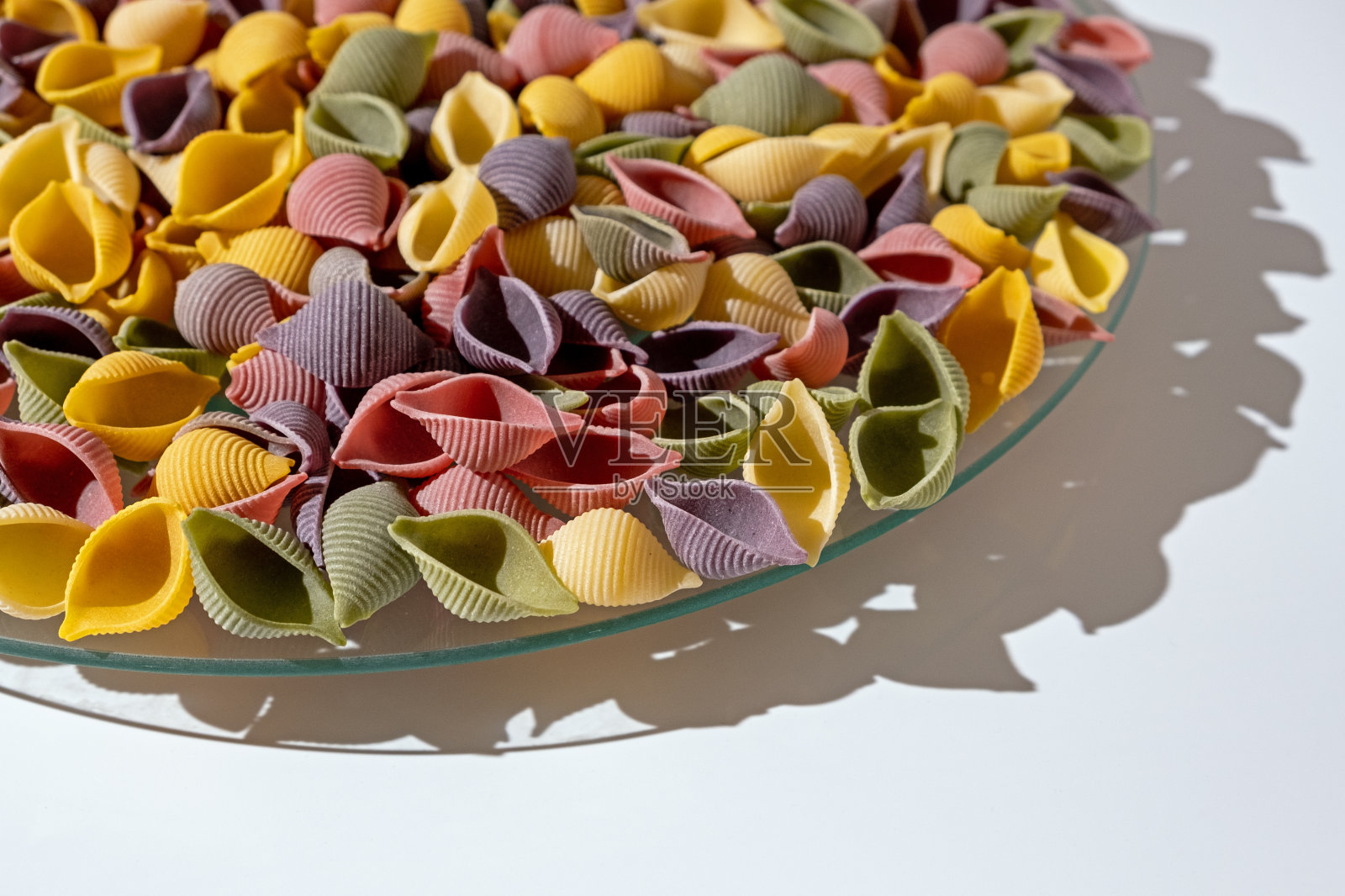 将意面放入盘中，将色彩鲜艳的生皮与菠菜和番茄混合。质感的意大利食物背景概念照片摄影图片