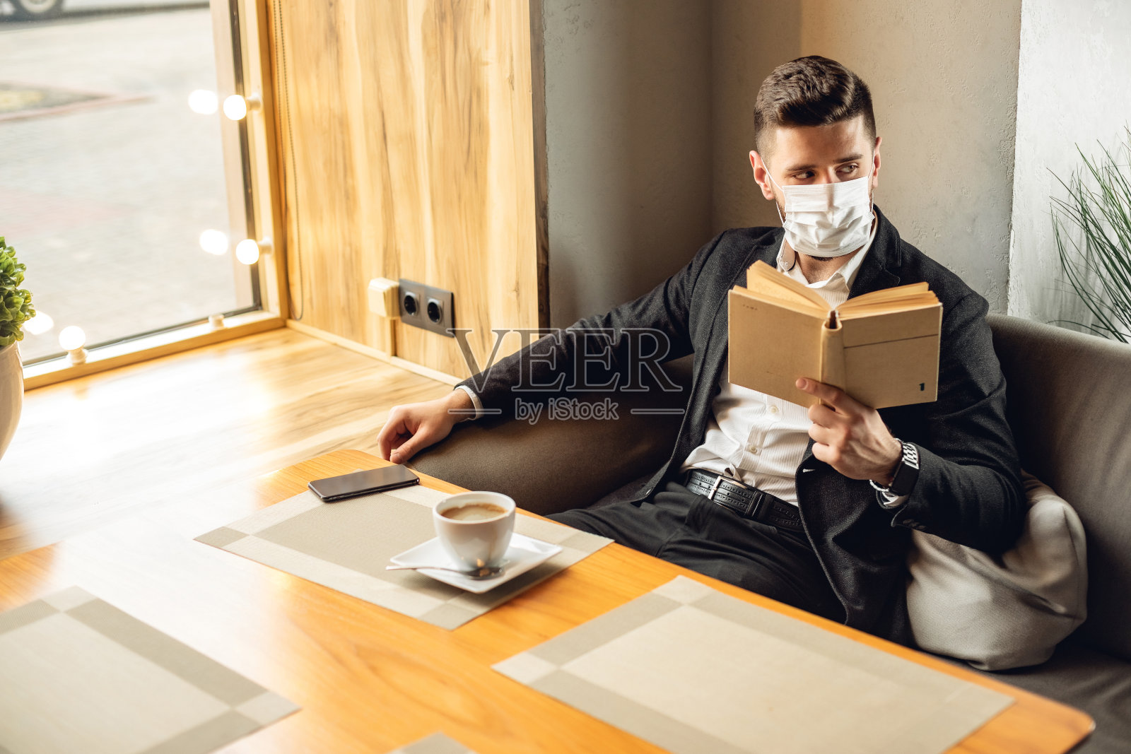 咖啡馆内戴口罩看书的年长的白人男子照片摄影图片